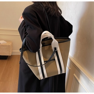 Lifestyle view of a large canvas tote bag with contrast webbing handles and leather trim