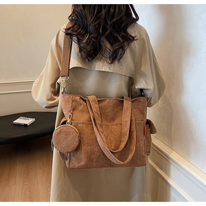 Detailed view of large brown corduroy tote bag with side pocket and matching round pendant
