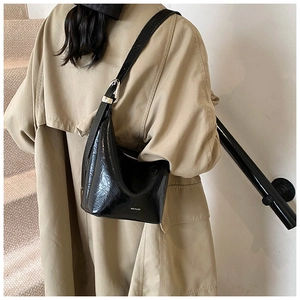 Detail of black glossy leather shoulder bag with white NO FILTER text and metal zipper