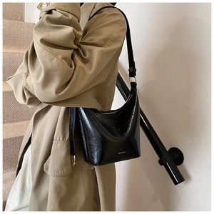 Glossy black hobo bag with NO FILTER print shown on model with tan trench coat