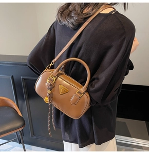 Detailed view of the brown leather bag with golden hardware and triangle plaque