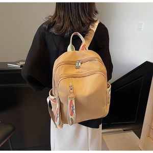 Detailed view of lightweight light brown nylon backpack featuring artistic graffiti straps