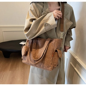 Detail of brown corduroy tote bag with side pocket and round coin purse attachment