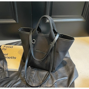 Detail of black canvas tote bag with leather trim and dual handles on a stylish background