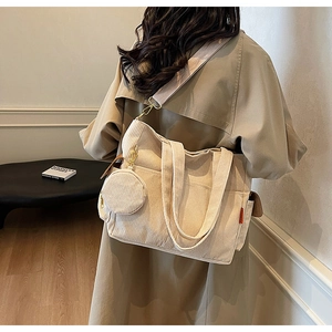 Detail of off-white corduroy tote bag with round coin purse and nylon strap on model