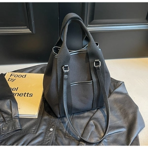 Detail of high-density black canvas tote featuring leather trim and dual strap system
