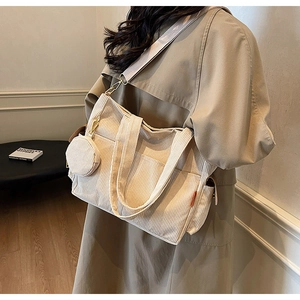 Detail of beige corduroy shoulder bag featuring wide fabric strap and matching coin purse