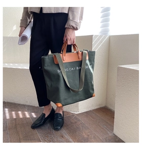 Detail of olive green canvas tote bag with leather trim and shoulder strap on a model