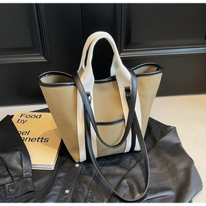 Detail of canvas tote bag with contrast leather trim and dual handles on leather jacket