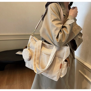 Detail of a beige corduroy tote bag showing large capacity and mini charm accessory