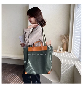 Detail showing high-capacity canvas tote bag with dark green fabric and brown leather handles