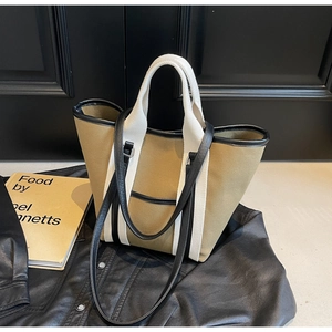 Detailed view of khaki canvas tote bag with black leather trim and dual shoulder straps