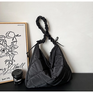 Detail of black quilted nylon tote featuring scrunchie style strap and diamond pattern