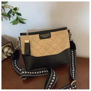 Detail view of khaki quilted texture and black leather contrast with striped strap