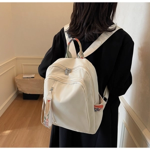 Detail of a beige canvas backpack featuring ethnic style woven patterns on the straps and pockets