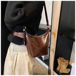 Detailed view of dark brown glossy bucket bag with adjustable strap and silver hardware