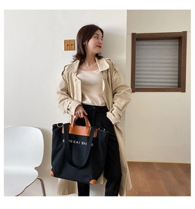 Detail shot of black canvas tote bag with brown leather handles and adjustable strap
