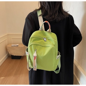 Detail view of bright green backpack featuring floral printed straps and multiple zip pockets