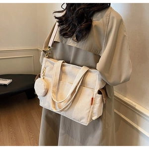 Detailed view of beige corduroy tote bag showing striped texture and round coin purse