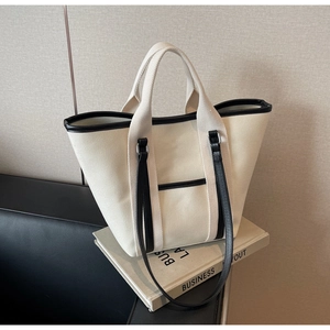 Detail of canvas tote bag with black trim, shoulder strap and minimalist front pocket