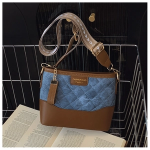 Close-up of quilted denim and brown leather bag with wide jacquard strap detail