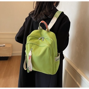 Detail of avocado green nylon backpack with colorful printed straps on a female model
