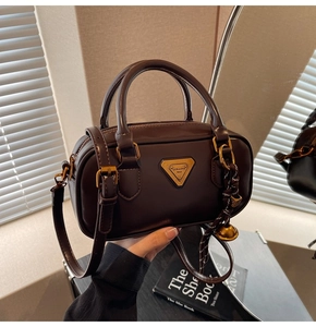 Close-up of brown leather Boston bag with gold logo and stylish knotted charm detail