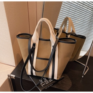 Detailed close-up of large khaki canvas tote bag with black leather trim and dual handles