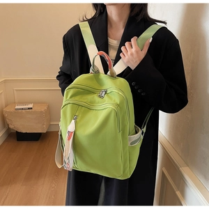 Detail of bright green nylon backpack with multi-color woven straps and zippers