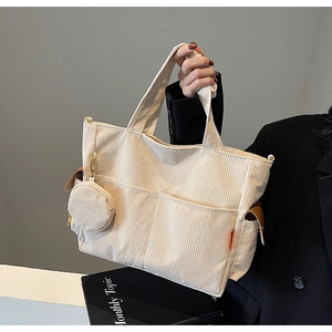 Detail of cream corduroy tote bag with side brown leather trim and round coin purse charm