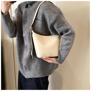 Detail of cream bucket bag in crinkled patent leather featuring NO FILTER text