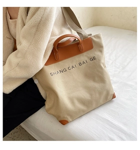 Detail of canvas tote bag with brown leather trim and handles on beige jacket