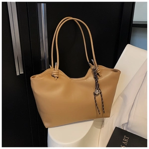 Detail of khaki tote bag with wavy top edge and stylish knotted handles on chair