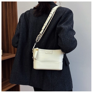 Close-up of white crocodile pattern leather bucket bag with gold chain strap detail