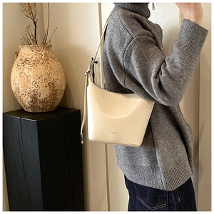 Detail of cream white underarm bag with NO FILTER text and adjustable silver buckle