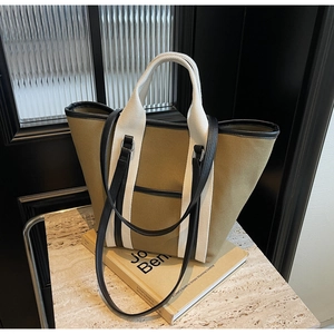 Detail of olive canvas tote bag with black leather trim and contrast straps on marble base
