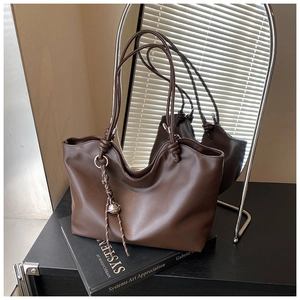 Detail of dark brown matte leather tote bag with silver ball charm and knot design