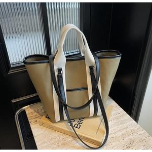 Close-up of olive green canvas tote bag with contrast straps and leather edge details