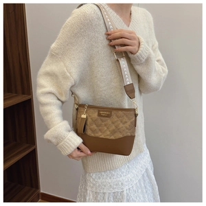Detail of brown quilted crossbody bag with wide jacquard strap and gold hardware