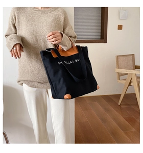 Detail of canvas tote bag showing thick fabric texture and brown leather handle stitching