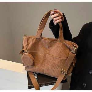 Detail of brown corduroy tote bag featuring vertical texture and round hanging coin purse