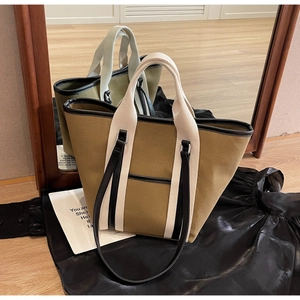 Detail of khaki canvas tote bag with black trim and wide off-white handles