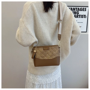 Brown quilted crossbody bag with patterned wide strap worn over a white dress