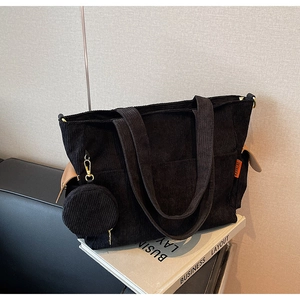 Detail of black corduroy tote bag with mini coin purse and stylish side leather accent