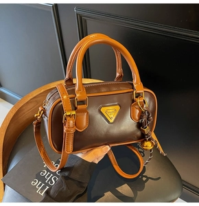 Detail view of a vintage Boston style handbag in dark coffee leather with tan handles