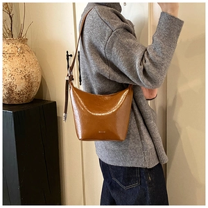 Detail view of caramel brown vintage underarm bag with glossy texture and metal buckle