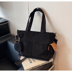 Detail of black corduroy tote bag with round coin purse and brown side pocket
