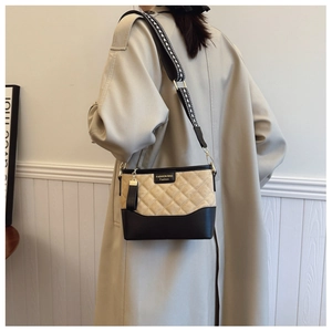 Quilted crossbody bag with wide arrow pattern strap and fashion label on shoulder