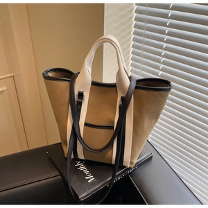 Detail of canvas tote bag showing contrast stitching and premium leather shoulder strap