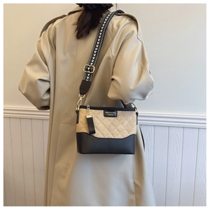 Close-up of quilted beige suede and black leather bag with geometric wide strap